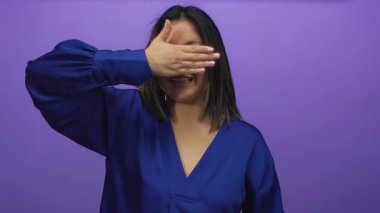 Mavi gömlek giyen, canlı mor bir duvarın önünde elleri üzerinde gülümseyen bir kadın, neşeli ve soyutlanmış bir sahne yaratıyor..