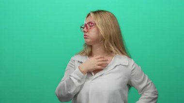 Gözlüklü bir kadın parlak yeşil bir arka plana karşı duruyor. Kendine güvenen ve günlük beyaz bir gömlekle odaklanmış. Basitliği ve gençliği vurguluyor..