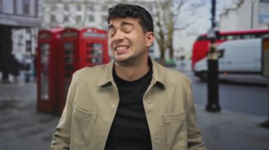 Londra caddesinde kırmızı telefon kulübesinin önünde derin derin nefes alan adam; sakin odaklanma rahatlama farkındalığı.