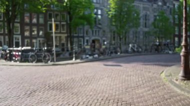 Güneşli gökyüzünün altında kaldırım taşı yolu boyunca parketmiş bisikletli Amsterdam Caddesi 'nin bulanık görüntüsü..