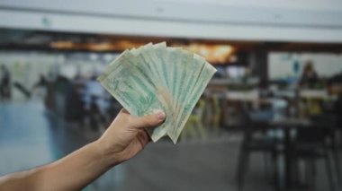 Birleşik Arap Emirlikleri 'ni elinde tutan adam bulanık bir restoranın arka planına sahip bir kahve dükkanında çalışıyor..