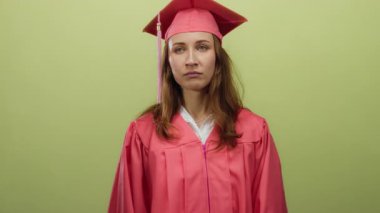 Mezuniyet elbisesi giyen kadın sarı arka planda tek başına duruyor. Eğitimini bitirdikten sonra yorgun ve motivasyonsuz görünüyor. Öğrenci hayatı yorgunluğunun özünü yakalıyor..