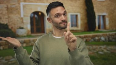 Kırsal Akdeniz 'de yaşayan genç bir adam, taş ev zeminine el ve parmak hareketleriyle işaret ediyor. Bir noktayı anlamlı bir şekilde aktarıyor, iletişim tarzını vurguluyor..