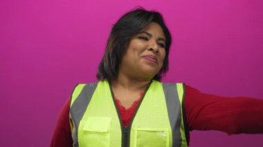 Ayrıca yansıtıcı yelek giyen İspanyol kadın parlak pembe duvara gülümseyip neşe ve güvenlik farkındalığı taşıyor..