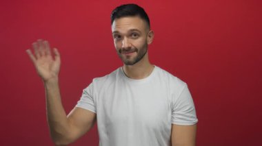 Beyaz bir tişört giymiş, parlak kırmızı bir zemine el sallayan ve gülümseyen İspanyol bir adam basit ama çarpıcı bir portrede sıcaklığını ve dostluğunu ifade ediyor..