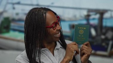 Elinde Tayvan pasaportuyla arka planda teknelerle gülümseyen bir kadın, seyahate hazır olduğunu ve yeni bir yolculuğa hazır olduğunu gösteriyor..