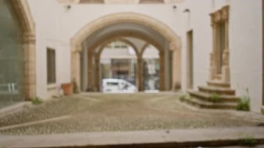 Tarihi bir üniversite kampüsündeki manastır manzarasının dağıtılması, yumuşak bir bokeh etkisi altında eski taş kemer yolları ve kaldırım taşı yolu yer alıyor..