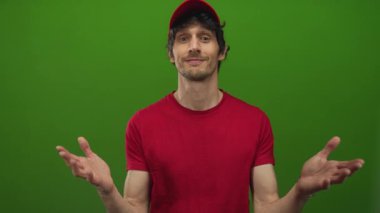 Teslimatçı geniş bir gülümseme içinde parlak yeşil arka plan karşısında stüdyoda açık avuçlar sunar; karşılama yardımı.