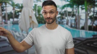 İspanyol adam gündüz vakti otelin yüzme havuzunda jest yapıyor..