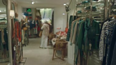 Modern dekorlu şık bir butikte alışveriş yapan, şık iç mekanlarda moda kıyafetleri ve aksesuarları olan, bulanık odaklı bir kadın hoş bir ortam yaratıyor..