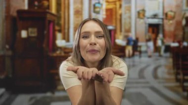 Kilisenin iç kısımlarında gülümseyen, huzurlu bir ortamda sıcaklık ve neşe taşıyan, bulanık mimari detaylar ve hafif aydınlatma ortamı olan bir kadın..