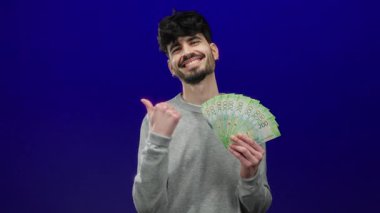 Mavi zemin üzerinde Rusya rublesi taşıyan bir adam, zenginlik ve güven gösterisi yapıyor..