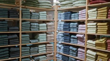 Bir kapalı mağaza vitrininde raflardaki renkli katlanmış tekstil yığınları canlı bir perakende seti oluşturur.