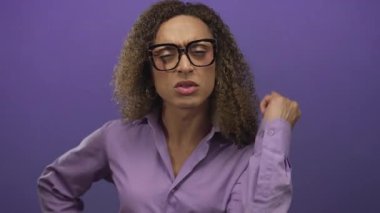 Gözlük takan transseksüel kadın, mor stüdyo ortamında izleyiciye parmak işareti yapıyor; hayal kırıklığı.