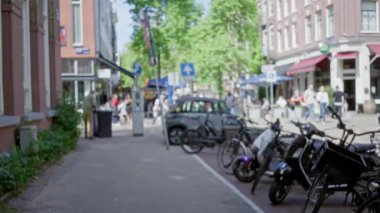 Güneşli bir günde bisiklet, insan ve şehir yaşamının olduğu bulanık şehir sahnesi.