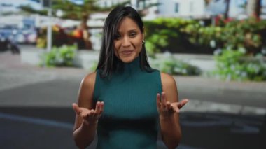 Açık sokak ortamında gülümseyen kadın, güneşli bir günde yemyeşil ve modern mimari ile kentsel arka planda mutluluk ve güveni resmediyor..