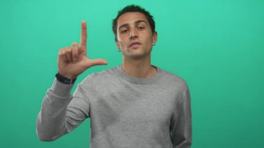 Küstah bakışlı İspanyol adam stüdyoda ezik işareti yapıyor ve kameraya işaret ediyor..