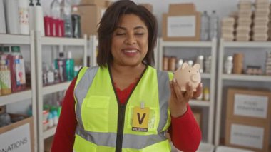 Yansıtıcı yelek giymiş bir kadın hayır kurumunda kumbarasını tutuyor..