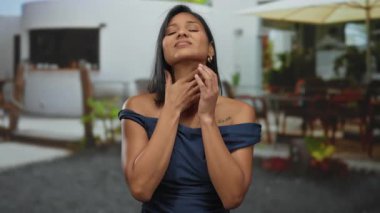 Genç bir kadın, caddedeki bir açık hava restoranında boğazını tutarken teras kafesinde kendini rahatsız hissediyor..