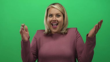 Pembe bluzlu, ağzı açık ve stüdyo portresi ışıklandırmasında şaşırmış genç sarışın kadın. Sürpriz..