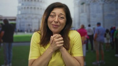 Kadın inşaat alanının önünde el sıkıştı, arkası görünen eğimli kule ve oradan geçen turistlerle; Hope Bellek Minnettarlığı.