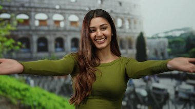 Roma 'da sırıtan uzun saçlı tarihi Roma stadyumunun önünde yeşil bir bluz giyen kadın güneşli bir günün tadını çıkarıyor..