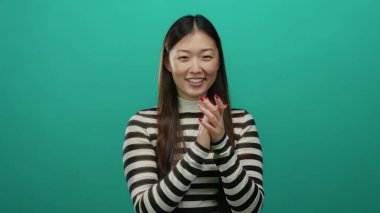 Çizgili tişörtlü bir kadın canlı yeşil bir arka plana gülümsüyor. Mutluluk ve pozitiflik gösteriyor..