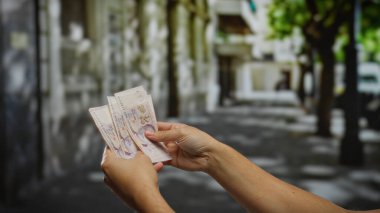 Bir şehir caddesinde Türk lirası banknotları tutan adam, bir şehir ortamında iş, yatırım ve finansmanı sembolize ediyor, para birimi ve ekonomik döviz üzerinde yoğunlaşıyor.