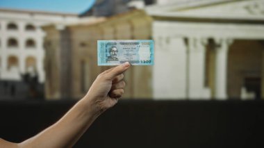 Bangladeş 'i elinde banknot tutan adam şehir dışında mimari geçmişi olan kalabalık bir şehir ortamında para sergiliyor..