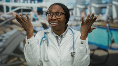 Lüks bir deniz havuzu alanında dışarıda duran kadın doktor. Stetoskop ve açık gökyüzü arka planına sahip güneşli limanda odaklanmış beyaz önlükle kafası karışmış görünüyor.