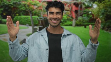 İspanyol adam gülümserken bir binanın önünde kollarını açıyor; sevinç iyimserliği kutlaması.