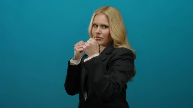 Cesur bir mavi arkaplan karşısında kendine güvenen bir kadın, dayanıklılık ve kararlılığın vücut bulmuş hali..