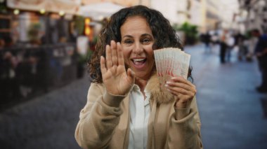 Kalabalık bir caddede elinde Singapur dolarlarıyla gülümseyen ve kameraya el sallayan bir kadın..
