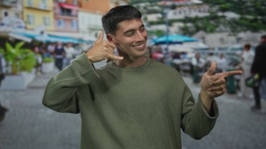 Yeşil eşofman giyen genç İspanyol adam sol eliyle işaret ediyor ve sağ eliyle sokakta işaret ediyor; bağlantı.