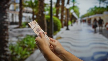 Şehir sokaklarında Meksika pezosu tutan adam yoğun bir şehir ortamında yatırım, iş ve finansal değişimi sembolize ediyor..