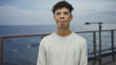 Gözlüklü genç adam ve beyaz kazak çantalı dudaklar seyahat güvertesinde hayat halkası okyanus ufkuna karşı huzur..