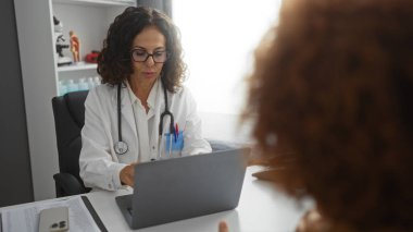 Hastane ortamında dizüstü bilgisayarı olan bir doktora danışıyorum. İçeride sağlık hizmetleri tartışması yapan iki kadın var..