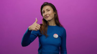 Başparmağıyla gülümseyen ve pembe arka planda oy veren bir kadın, destek ve sivil nişanı ifade ediyor..