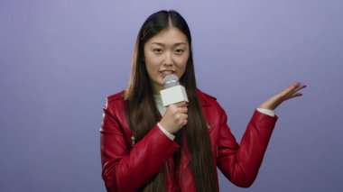 Mikrofona konuşan bir kadın izole edilmiş mor arka planda kırmızı ceket giymiş, kendine güvenen ve ifade veren bir kadın..