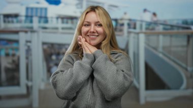 Gezgin güvertesinde günlük kıyafetleriyle gülümseyen genç sarışın kadın güneşli bir günde açık deniz manzarasının keyfini çıkarıyor lüks bir teknede özgürlük ve macerayı kucaklıyor..