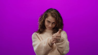 Canlı pembe bir arka planda, rahat bir süveter giyen, anlamlı ve neşeli bir anı yakalayan, kendine güvenen bir kadın..