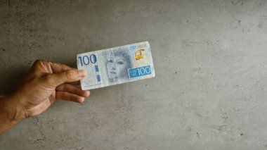 İsveç 'te somut arkaplan, para birimi ve finansal temaları vurgulayan 100 krona' lık banknot tutan adam.