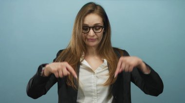 Mavi stüdyoda gözlüklü, ceketli beyaz gömlekli ve düşünceli bir kadını işaret ediyor..