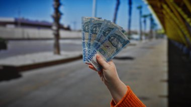Kentsel sokak ortamında el ele tutuşan Macar Forint banknotları, doğal ışıklandırmalı bir şehir ortamında iş ve mali işlem temaları yansıtıyor..
