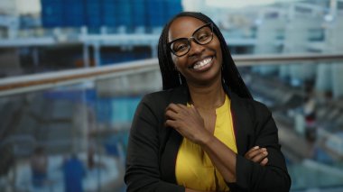 Deniz kenarındaki bir teknede gülümseyen bir kadın gözlüklü ve canlı bir atmosferi olan sarı gömlekli bir kadın limanda çekilen neşeli bir anı gösteriyor..