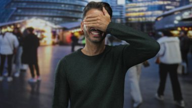 Kalabalık şehir caddesinde, aydınlanmış pazar tezgahlarının ve geçen yayaların yakınındaki gözlerle gözlerini kapatan adam; gizem.