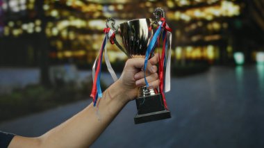 Gece vakti şehir sokaklarında zafer, başarı ve açık hava sahnesinde elde edilen başarıyı simgeleyen kurdeleli bir adamın eli..