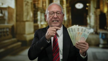 Kilise içinde Czech Koruna banknotları tutan kıdemli bir adam, dini bir ortamda iş ve zenginliği simgeliyor..