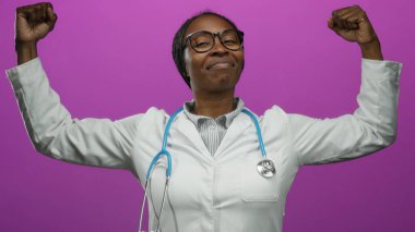 Steteskoplu kendine güvenen kadın doktor canlı pembe arka plana karşı zafer için kollarını kaldırıyor..