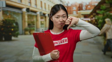 Kırmızı gömlekli bir kadın arka planda binaları olan bir şehirde pano tutuyor..